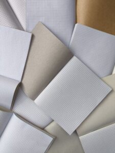 A collection of open notebooks with grid paper and plain brown covers