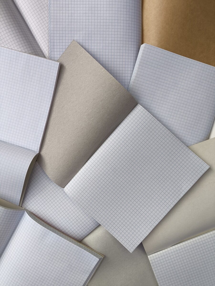 A collection of open notebooks with grid paper and plain brown covers
